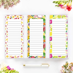 May include: Three colorful grocery list notepad pads with fruit designs. The pads have a white background with a border of various fruits, including watermelon, lemons, bananas, and cherries. The pads are lined for writing.