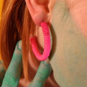 A close up view of the Helen Hoop earrings in pink on a model.
