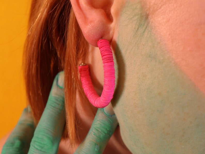 A close up view of the Helen Hoop earrings in pink on a model.