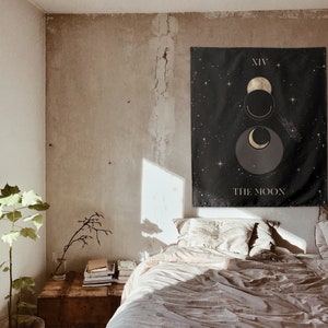 Puede incluir: Un tapiz negro con estrellas doradas y un dise&ntilde;o de luna creciente. El tapiz tiene el texto "XIV THE MOON".