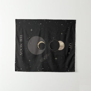 Puede incluir: Tapiz negro con un fondo de cielo estrellado de noche. El tapiz presenta tres lunas en diferentes fases, con el texto "THE MOON" y el n&uacute;mero romano "VII" en dorado.