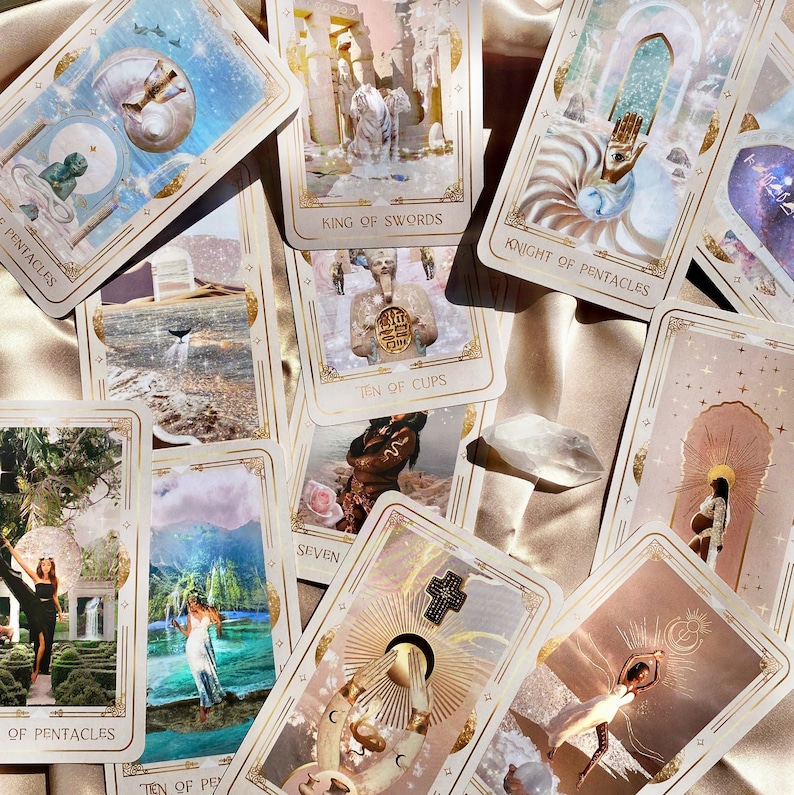 May include: A collection of tarot cards with various illustrations and gold accents, including the "King of Swords" and "Knight of Pentacles" cards. The cards are scattered on a satin surface, with a clear crystal in the center. The overall theme is divination and spirituality.