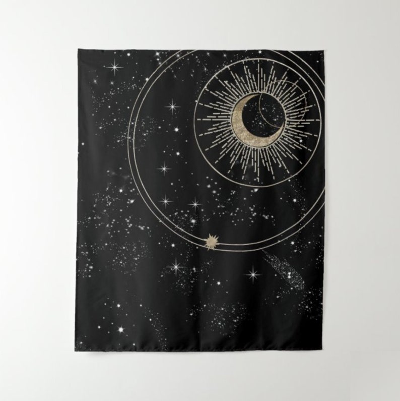 May include: A black tapestry featuring a gold crescent moon and sun design. The moon is encircled by a ring of stars, and the sun has rays radiating from it. The background is a dark blue with white stars.