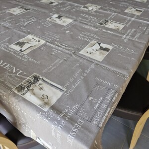 Peut inclure: Une nappe grise avec un thème de bistrot français vintage. La nappe présente un motif répété d'illustrations en noir et blanc de nourriture, de boissons et de texte en français. Le texte comprend "Menu", "Dessert", "Plat du Jour" et "Bistrot de l'Amitie".
