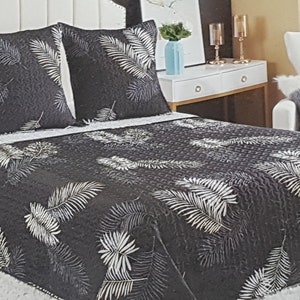 Peut inclure: Une couvre-lit à motifs noirs et blancs avec un fond blanc et des motifs de feuilles noires. La couvre-lit est sur un lit avec deux oreillers assortis.