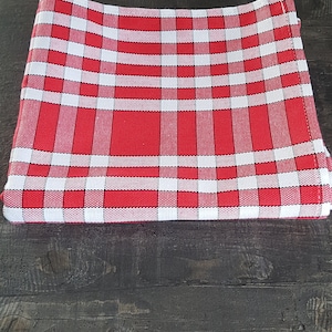 Peut inclure: Nappe à carreaux rouges et blancs pliée sur une surface en bois foncé.