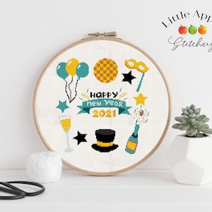 Op de afbeelding: Een witte borduurring met een kruissteekontwerp met een champagnefluit, een hoge hoed, een feestmasker, ballonnen en de tekst "Happy New Year 2021".