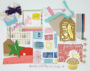 May include: A collection of colorful paper crafting supplies with a birthday theme. The supplies include a gold tag with the text "Happy Birthday", a pink and white card with the text "Party!", a blue and white card with a girl wearing a party hat, and a pink and white card with the text "Party! Treat yourself!"