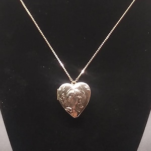 1928 TM. Cameo style heart shaped gold tone locket necklace. In great preowned condition.