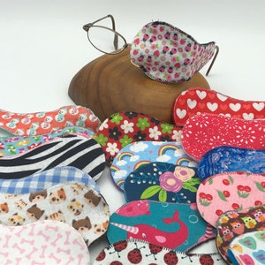 May include: A collection of colorful fabric eye patches with various patterns, including hearts, flowers, animals, and geometric designs. The patches are designed to cover one eye and are ideal for eye care.