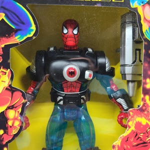 Puede incluir: Una figura de acci&oacute;n roja y negra de Spider-Man con un traje de armadura negro y plateado. La figura sostiene un arma plateada y est&aacute; de pie sobre un fondo amarillo. La figura es parte de la l&iacute;nea de juguetes Marvel Universe.
