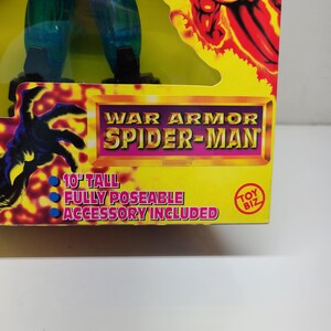 Puede incluir: Una figura de acci&oacute;n azul y verde de Spider-Man con un traje de armadura de guerra. La figura mide 25,4 cm de alto y es completamente articulada. El empaque incluye el texto "War Armor Spider-Man" y "Toy Biz".