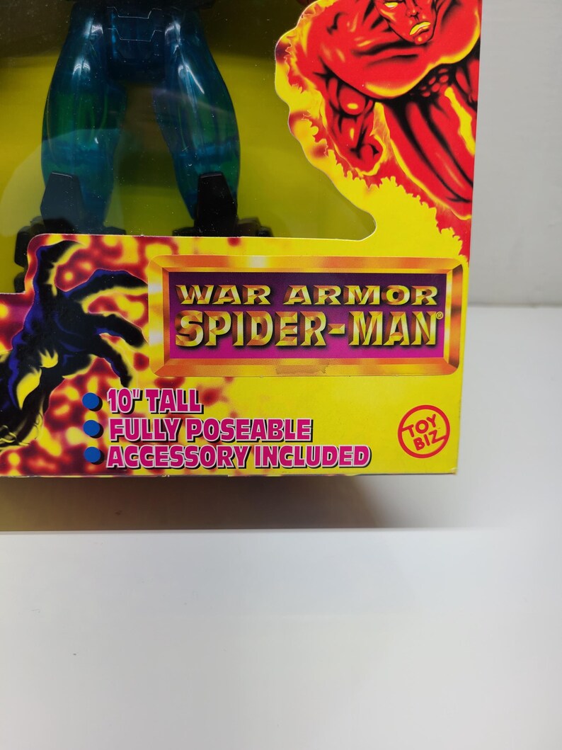 Puede incluir: Una figura de acci&oacute;n azul y verde de Spider-Man con un traje de armadura de guerra. La figura mide 25,4 cm de alto y es completamente articulada. El empaque incluye el texto "War Armor Spider-Man" y "Toy Biz".