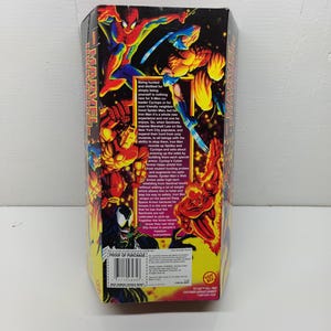Puede incluir: Una caja colorida con personajes de Marvel, incluyendo Spider-Man, Wolverine, Iron Man, Venom y la Antorcha Humana. La caja tiene un esquema de color rojo, amarillo y negro con la palabra "MARVEL" impresa en letras blancas grandes. El texto en la caja describe los personajes y sus habilidades. La caja tambi&eacute;n incluye un c&oacute;digo de barras "PROOF OF PURCHASE".
