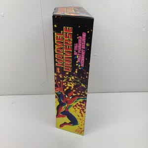 Puede incluir: Una caja negra con una imagen roja y amarilla de Spider-Man en el lateral. La caja dice "Marvel Universe" y "10" tall fully poseable accessory included."