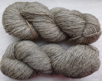May include: Two skeins of gray wool yarn. The yarn is a medium weight and has a slightly fuzzy texture.