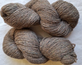 May include: A skein of brown yarn with subtle variations in color. The yarn appears to be a natural fiber, with a slightly textured appearance. The yarn is tightly wound, and the overall effect is rustic and inviting. Ideal for knitting or crocheting projects.