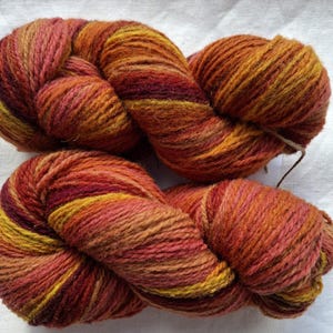 Wolle Garn zum Stricken, Hochwertiges mehrfarbiges orange, rot, gelb gestreiftes Wollgarn. Natürliches Lanolin-Garn.