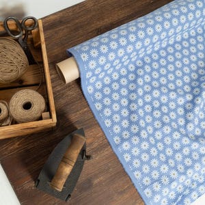 light blue linen fabric with white daisy flower print on wooden table