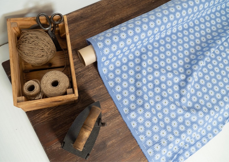 light blue linen fabric with white daisy flower print on wooden table