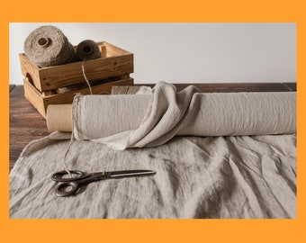 May include: A roll of natural linen fabric with a wooden crate of twine spools and a pair of scissors on a wooden table.
