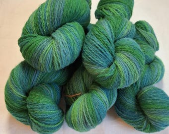 May include: A collection of green and blue yarn skeins. The yarn is a mix of vibrant greens and blues, creating a textured appearance. The skeins are tightly wound, suggesting they are ready for knitting or crocheting projects. The image showcases the yarn's color variations and texture.