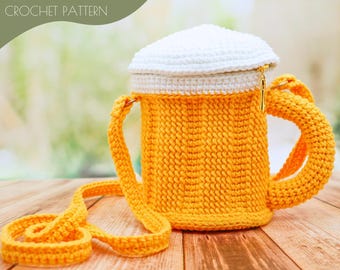 May include: A crocheted beer mug purse with a white top and a yellow body. The purse has a long strap and a handle.