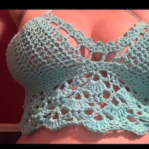 May include: A light blue crochet top with a delicate, intricate pattern. The top has a low-cut neckline and a cropped length.