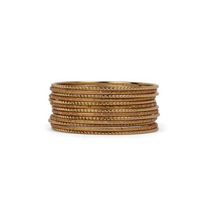 Könnte beinhalten: Ein Set aus 12 goldfarbenen Armreifen mit strukturiertem Design. Die Armreifen sind übereinander gestapelt.