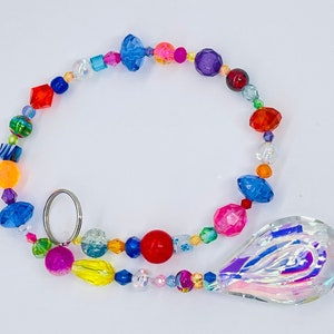 May include: A colorful beaded suncatcher with a large iridescent crystal teardrop. The beads are in various colors, including red, orange, yellow, green, blue, purple, and pink.