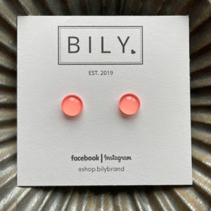 May include: A pair of small, round, peach-colored earrings on a white card with the text "BILY. EST. 2019 facebook | instagram @shop.bilybrand"