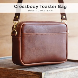 Könnte beinhalten: Eine braune Leder-Umhängetasche mit rechteckiger Form und einer Vordertasche. Die Tasche hat einen goldenen Reißverschluss und Beschläge sowie einen braunen Riemen. Der Text "Crossbody Toaster Bag DIGITAL PATTERN" wird oben angezeigt.