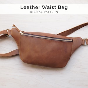 Op de afbeelding: Een bruine leren heuptas met ritssluiting en verstelbare riem. De tas heeft een rechthoekige vorm en een goudkleurige ritssluiting. De tekst "Leather Waist Bag DIGITAL PATTERN" staat bovenaan.