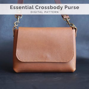 May include: A brown leather crossbody purse with a flap closure and a shoulder strap. The purse has gold-colored hardware and the text "Essential Crossbody Purse DIGITAL PATTERN" at the top.