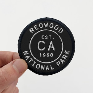 May include: Black and white embroidered patch with the text "Redwood National Park" and "Est. CA 1968" in a circle.