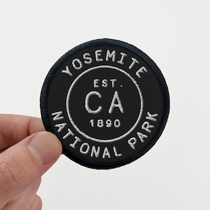 May include: Black and white embroidered patch with the text "Yosemite National Park" and "Est. 1890" inside a circle with the letters "CA" in the center.