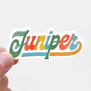 May include: A sticker with the word "Juniper" written in a colorful, retro font. The letters are outlined in white and the background is white.