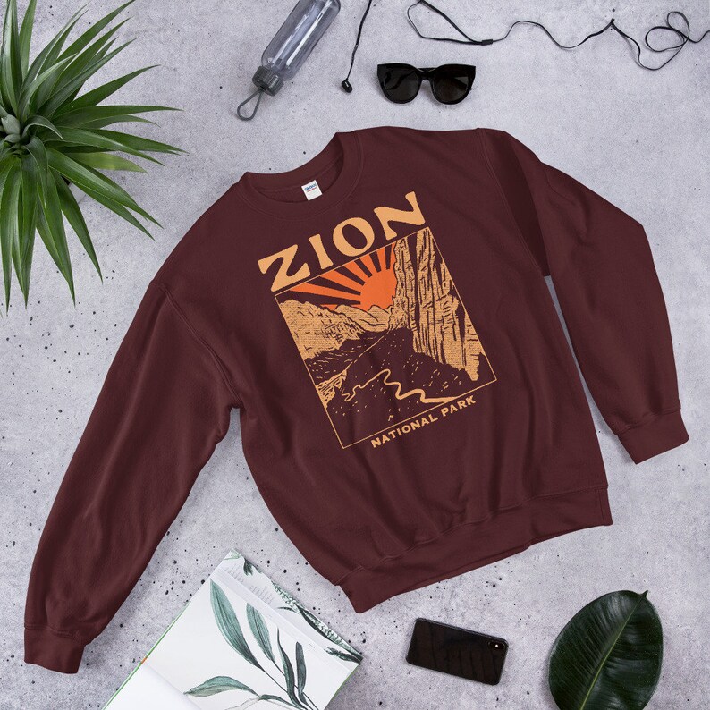 Maroon Zion National Park Utah Vintage-Style Crewneck and long sleeved jumper. It has Zion National Park written on it and a square drawn image of a canyon and river running through it