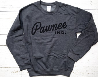 Peut inclure: Un sweat-shirt gris foncé avec le texte "Pawnee IND." imprimé en noir sur le devant.