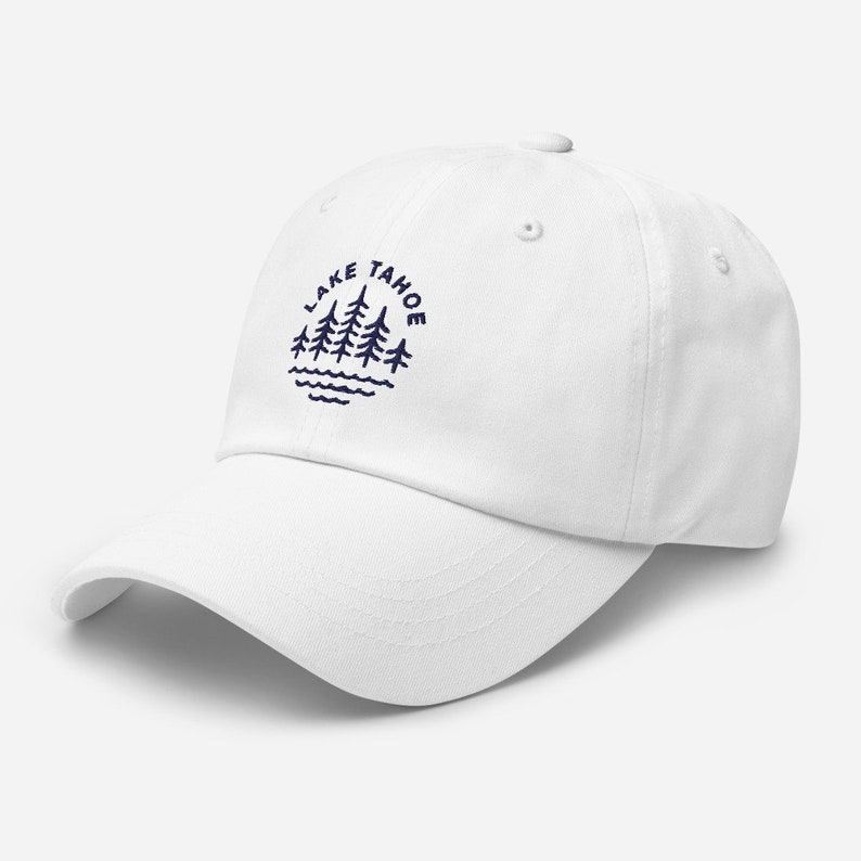 May include: White baseball cap with a navy blue embroidered design of pine trees and the text "LAKE TAHOE" in a circle.