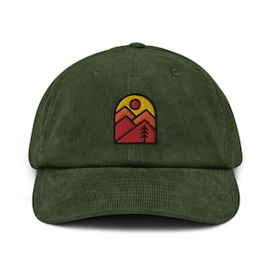 May include: A green corduroy baseball cap with an embroidered patch of a mountain range with a sun and a tree. The patch is in shades of red, orange, and yellow.
