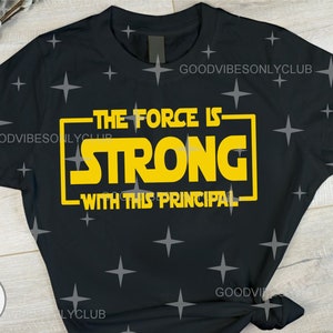 Puede incluir: Camiseta negra con un gr&aacute;fico amarillo que dice "The Force Is Strong With This Principal".