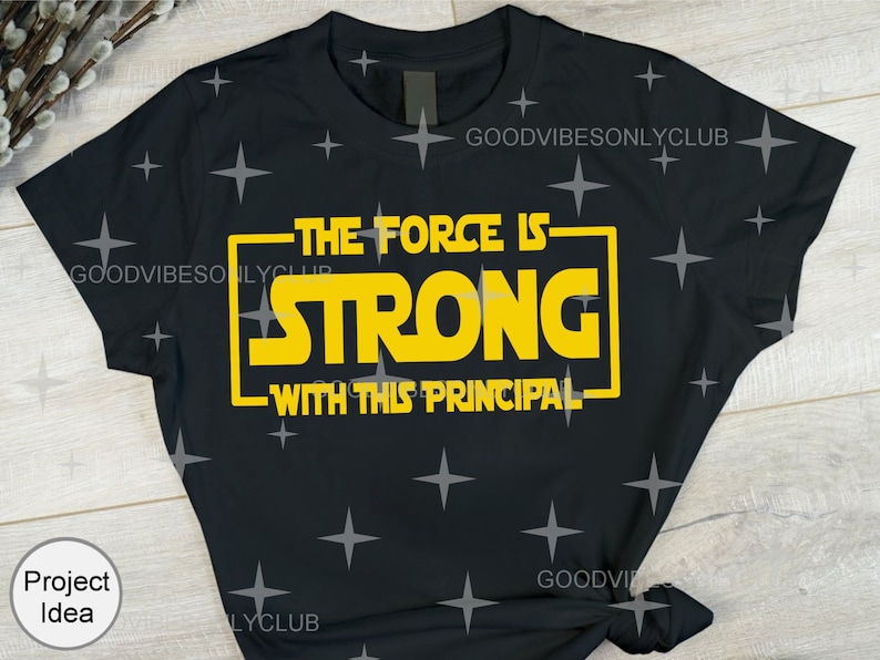 Puede incluir: Camiseta negra con un gr&aacute;fico amarillo que dice "The Force Is Strong With This Principal".