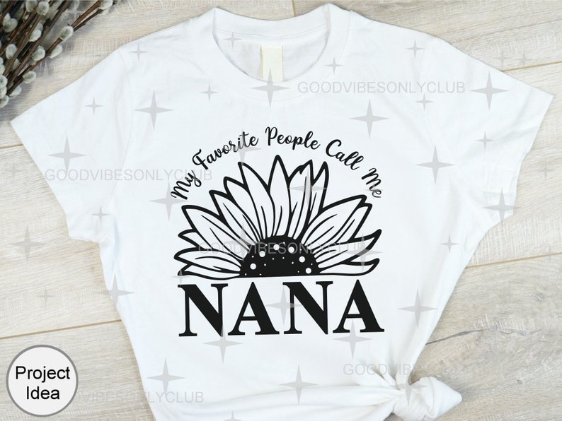 May include: White t-shirt with a black sunflower graphic and the text "My Favorite People Call Me Nana".