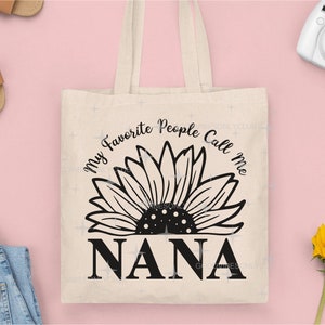 May include: A white tote bag with black text and a sunflower graphic. The text reads "My Favorite People Call Me Nana".