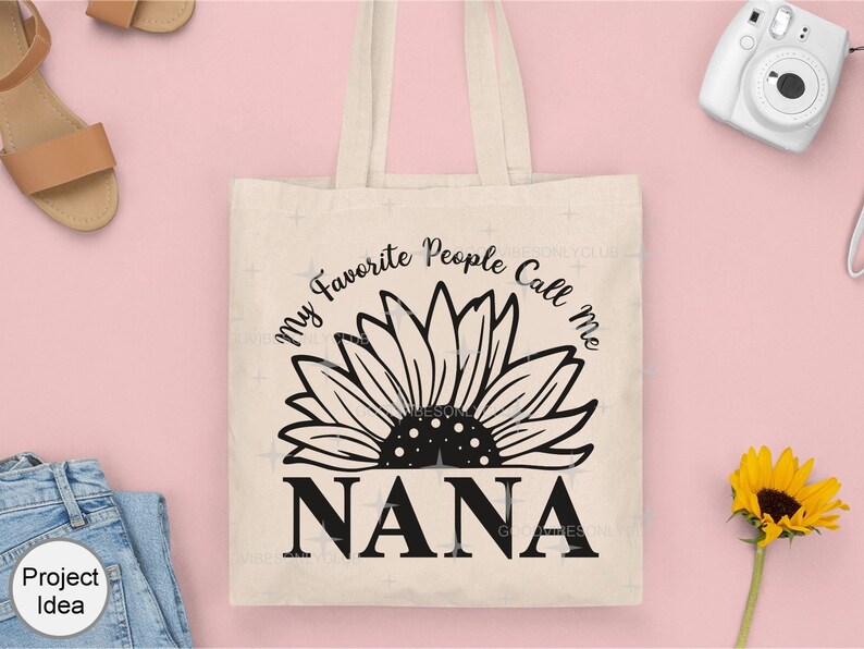 May include: A white tote bag with black text and a sunflower graphic. The text reads "My Favorite People Call Me Nana".