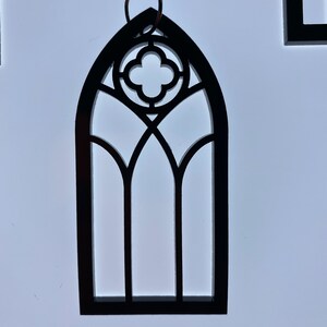 May include: Black wooden cutout of a gothic arch window with a quatrefoil design.