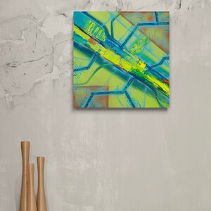 May include: Abstract painting with a yellow, green, and blue colour scheme. The painting features a series of intersecting lines and shapes, creating a dynamic and energetic composition.