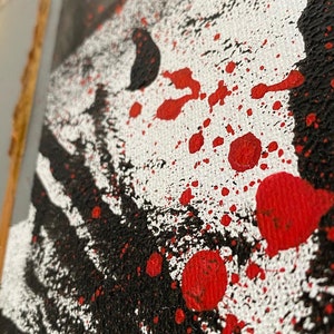 May include: Abstract art painting with black and red paint splatters on a white canvas.