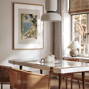 May include: A dining room scene featuring a rectangular table with a white and gold patterned top, surrounded by woven rattan chairs. A framed artwork depicts a coastal view. A white pendant light hangs above the table, and a window with a bamboo shade is visible.
